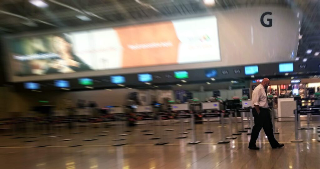 Geovane Souza caminhando sozinho no Aeroporto Galeão, ilustrando a solidão e a rotina exaustiva de quem trabalha nos bastidores de eventos.