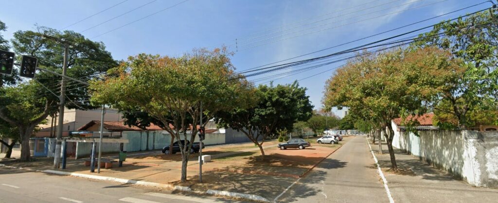 Vista panorâmica do ponto de ônibus na Avenida Ouro Fino em São José dos Campos, com árvores e uma rua residencial tranquila ao fundo sob céu claro.