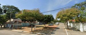 Vista panorâmica do ponto de ônibus na Avenida Ouro Fino em São José dos Campos, com árvores e uma rua residencial tranquila ao fundo sob céu claro.